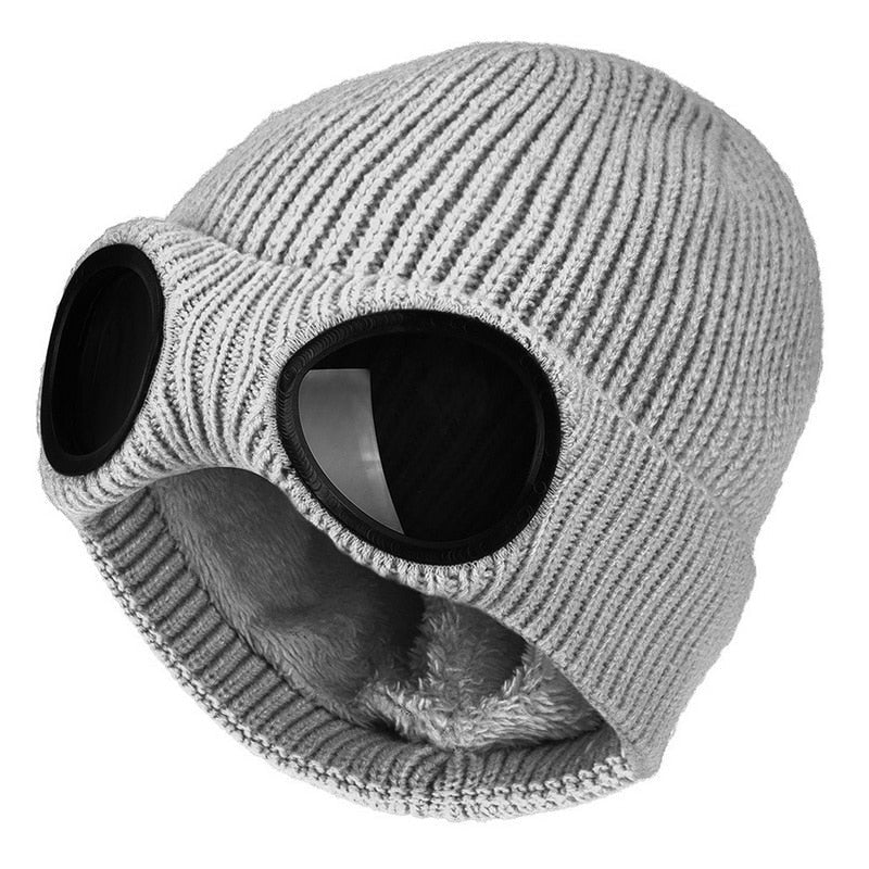 Detaljbild på den svarta stickade mössans mönster och de silverfärgade integrerade goggles