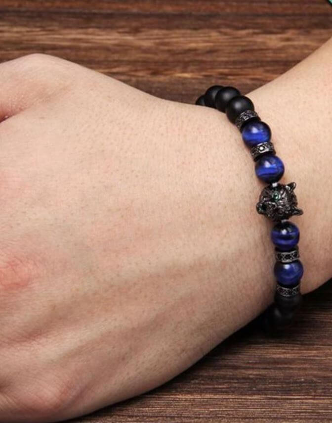 Närbild på unisex tigeröga armband med vargcharm. Äkta natursten för energi och stil.