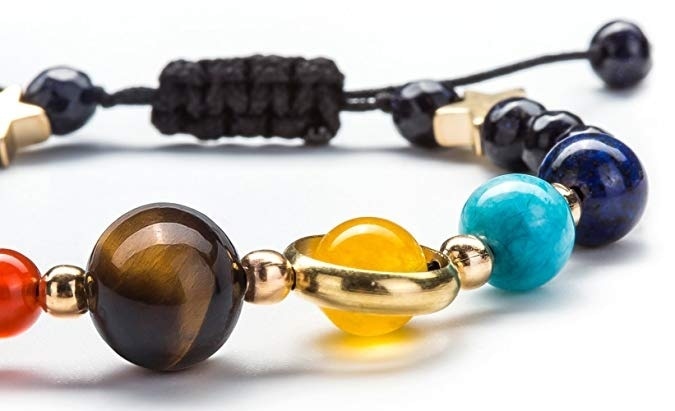 Närbild av chakrainspirerat unisexarmband med polerade naturstenar som representerar solsystemet, en unik present.