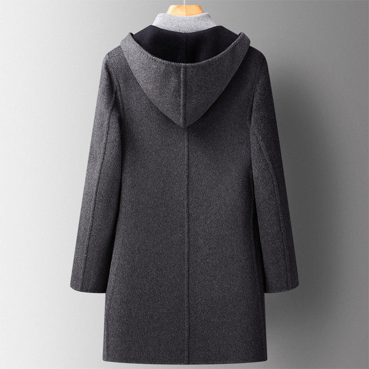 Man bär svart vändbar herrjacka med huva. En modern vinterjacka, perfekt för urban herrmode.