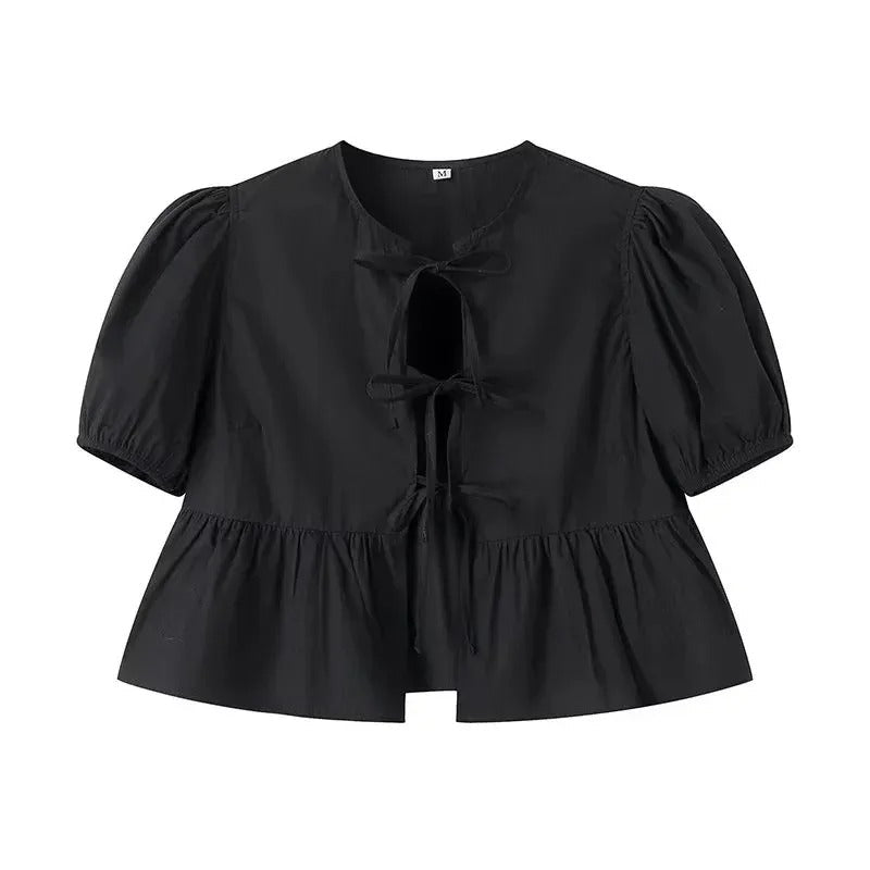 Vit damtopp med volang, knytning och trendiga puffärmar. Perfekt för sommar och en feminin stil.
