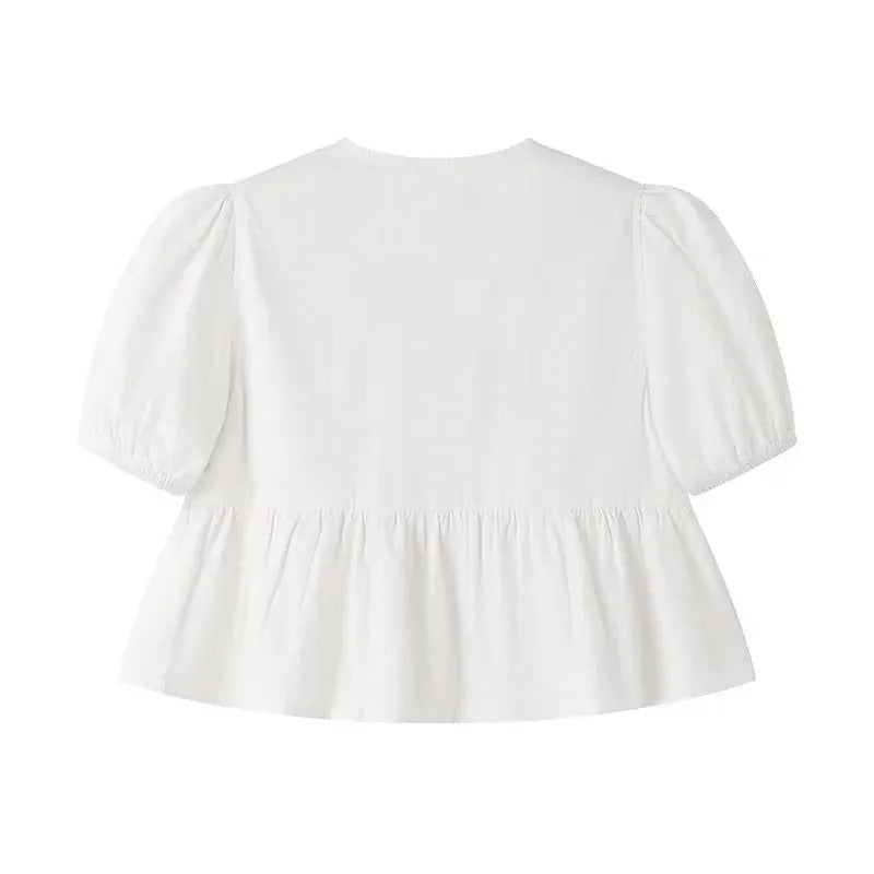 Trendig damtopp med korta puffärmar, volanger och knytning. En feminin croptop i vit färg.