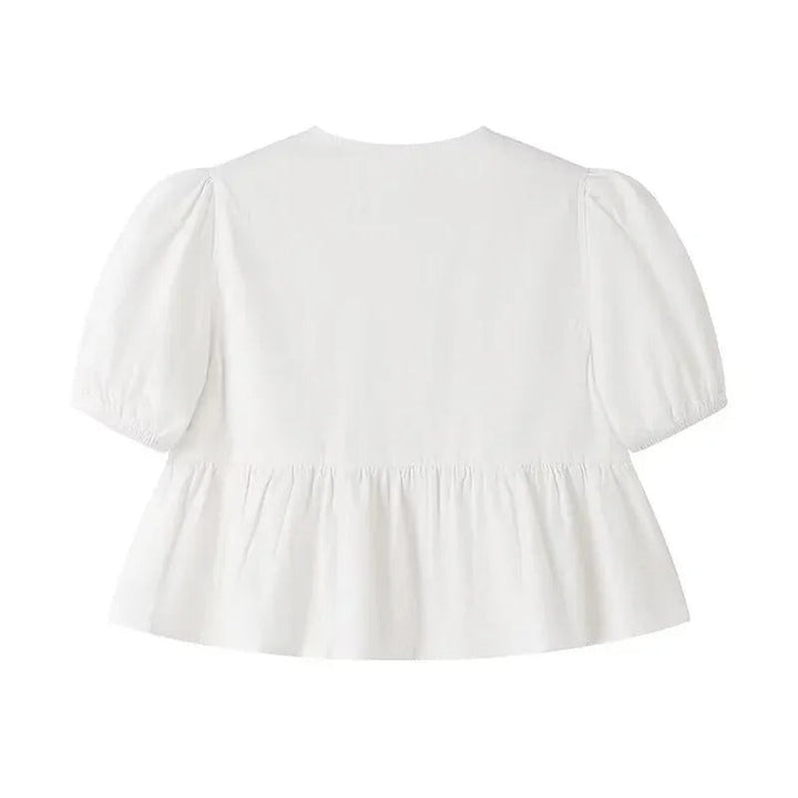 Trendig damtopp med korta puffärmar, volanger och knytning. En feminin croptop i vit färg.