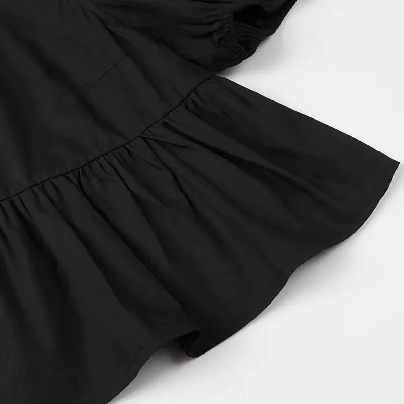 Feminint svart volangtopp med korta puffärmar och knytning, en trendig croptop för sommarlooken.