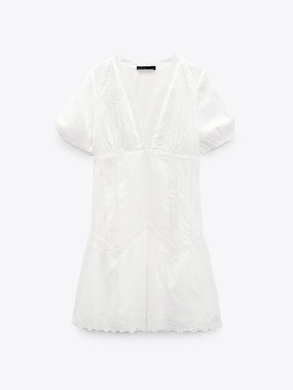 Trendig vit miniklänning med romantiska detaljer; V-ringning, utsökt broderi och fluffiga ärmar.