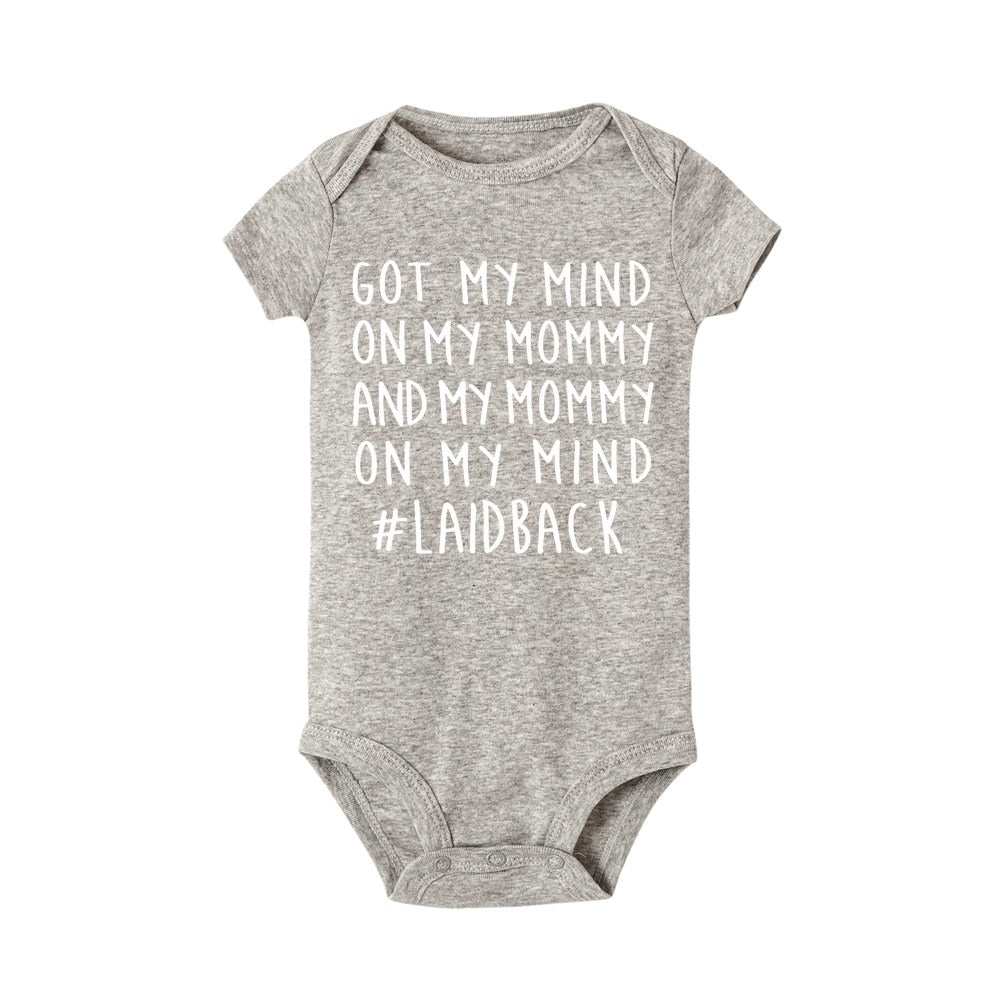 Vit unisex babybody i mjuk bomull med svart 'Älskar Mamma' tryck, perfekt för spädbarn.