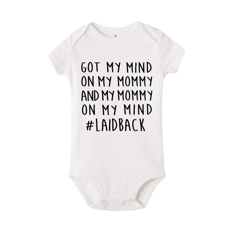 Hängande vit unisex babybody i bomull för spädbarn, med tryck som presenttips.