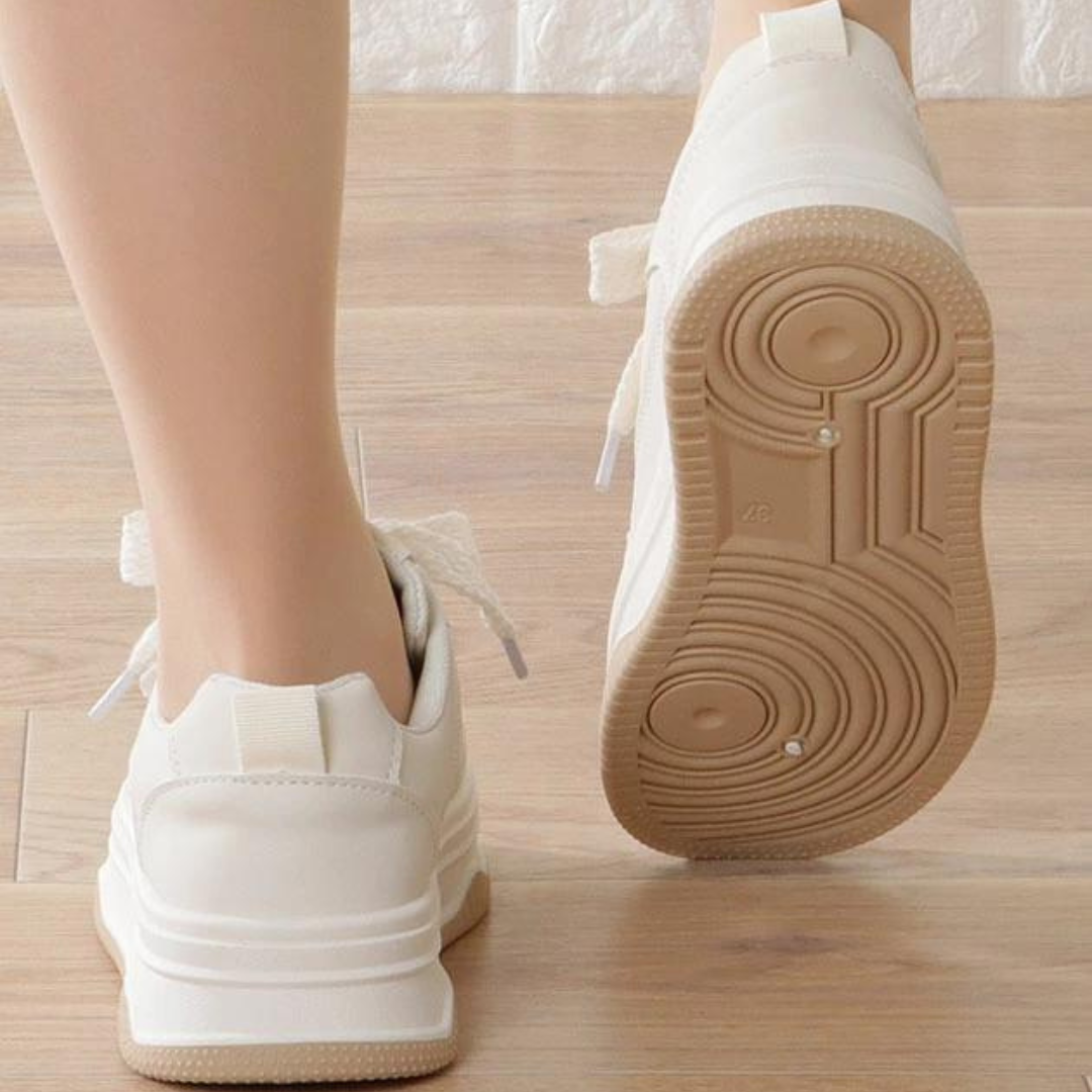 Närbild på vita chunky sneakers, visar detaljer av ovandel, snörning och den tjocka platåsulan.