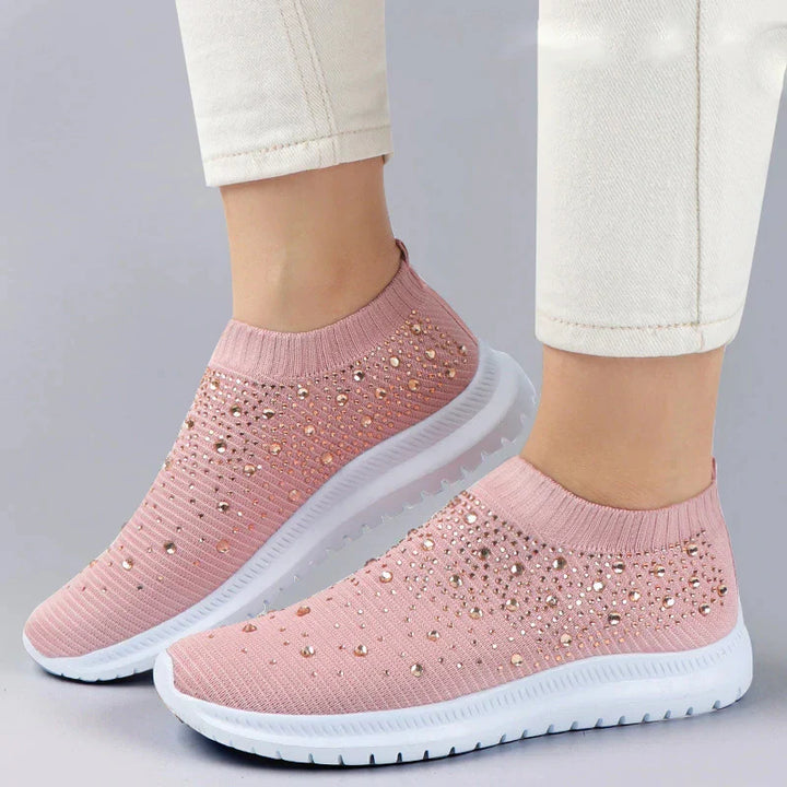 Bekväma slip-on damsneakers av vit mesh med glittrande strass, perfekta för fritid eller sport.