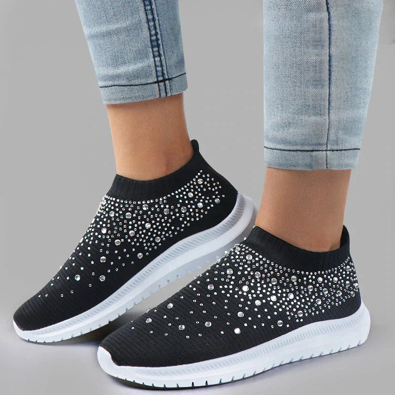 Närbild av ventilerande mesh-material och strassdetaljer på vita damsneakers, bekväma fritidsskor.